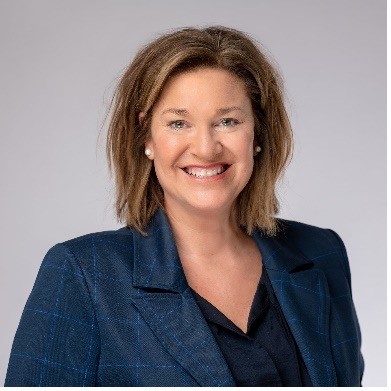 A woman smiles in a blue jacket and blue shirt.