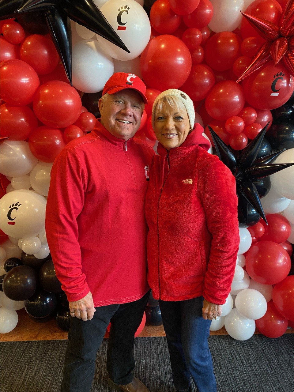Jerry Fritz and his white stand together in red and in front of red, black and white balloons.