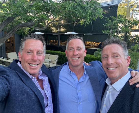 The Aronson brothers take a selfie in blue suit jackets and collared shirts.