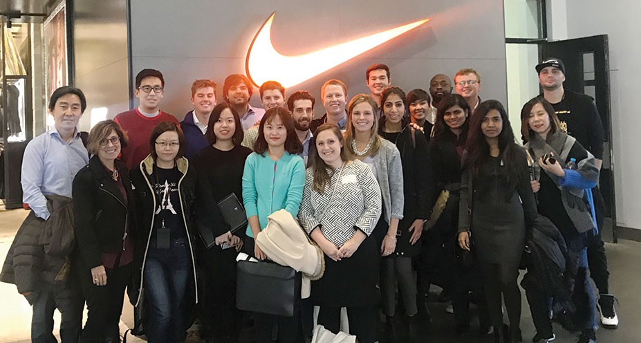 Lindner MBA students and faculty pose in front of an illuminated Nike logo in Shanghai