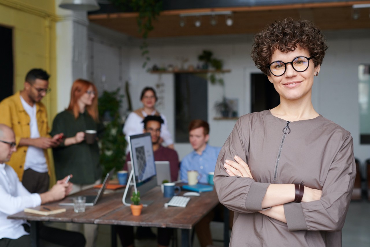 Woman smiling at camera in office with colleagues