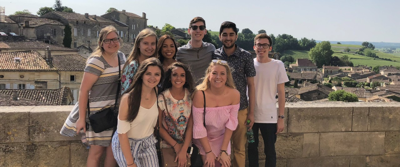 Group of UC students on bridge in Italy overlooking landscape.