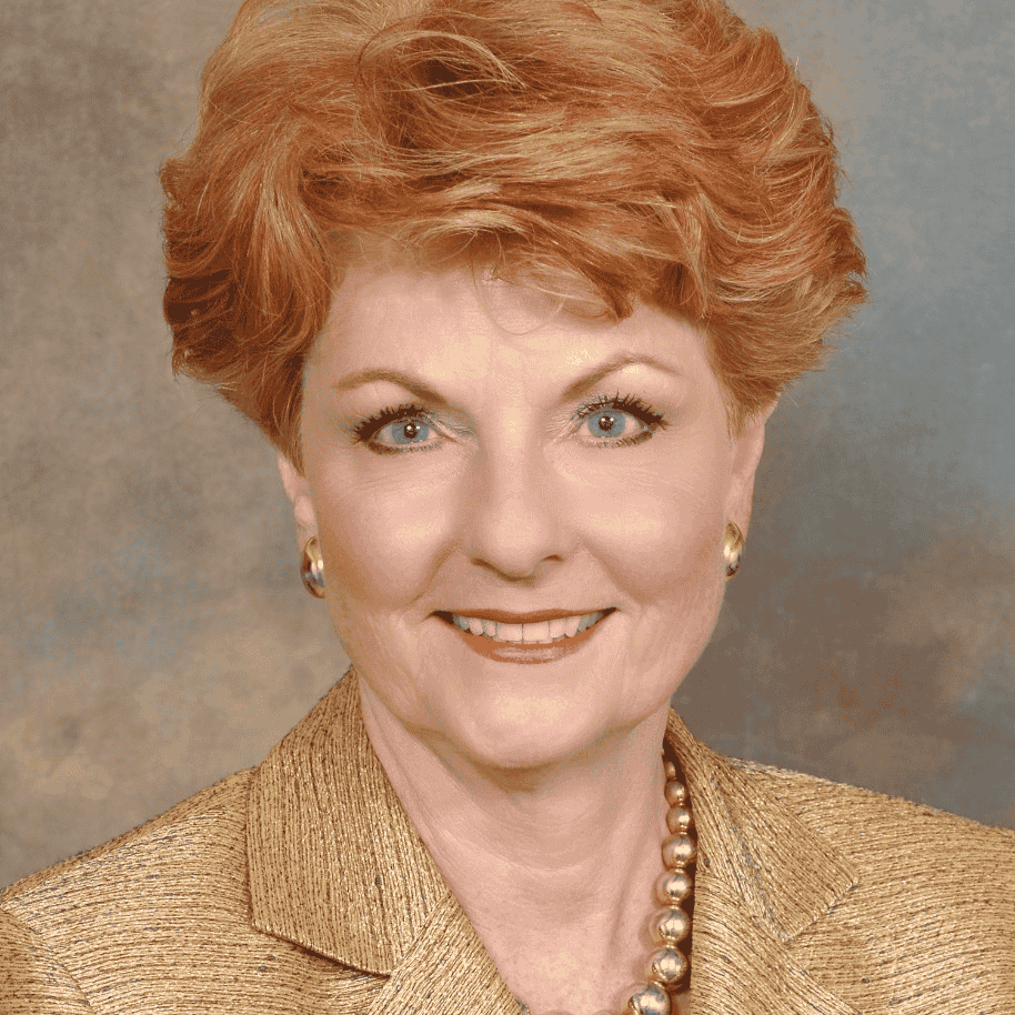 A woman wears a tan jacket and smiles.